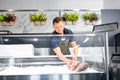 Male seller putting trout to fridge at fish shop