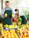 Male seller of vegetable department of store replenishing showcase with apple, put ones on showcase Royalty Free Stock Photo