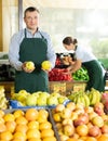 Male seller of vegetable department of store replenishing showcase with apple, put ones on showcase Royalty Free Stock Photo