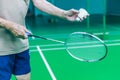 Male Senior Badminton single player hand holds white shuttle cock, ready to serve forehand with racket on green court. Sport, Game Royalty Free Stock Photo