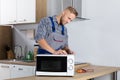 Male Serviceman Using Screwdriver To Repair Microwave