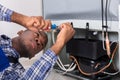 Male Serviceman Working On Fridge With Screwdriver Royalty Free Stock Photo