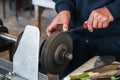 male sharpener sharpens a knife blade on a knife sharpening machine in workshop Royalty Free Stock Photo