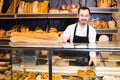 Male shop assistant demonstrating fresh delicious pastry in bake