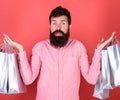 Male shopaholic with long beard isolated on red background. Hipster in pink shirt with stylish beard holding silver