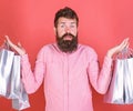 Male shopaholic with long beard isolated on red background. Hipster in pink shirt with stylish beard holding silver