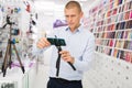 Male shopper chooses smartphone tripod at store