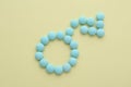 Male sign with bent arrow of blue pills symbolizing potency problems on beige background flat lay