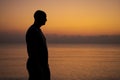 Male silhouette on background sea at sunset looks to side alone. Man enjoying Royalty Free Stock Photo