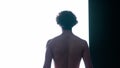 Male silhouette close up against digital wall in dark club. Man topless walking towards big digital screen with strobing