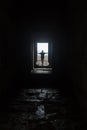 Male silhouette in empty interior looking in window, lit by dramatic sunlight.