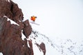 Male skier athlete doing a drop jump from a cliff in the snowy mountains on a cloudy day in winter