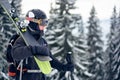 Male skier in goggles with professional ski equipment on his shoulders standing on slope top before skiing in mountains. Royalty Free Stock Photo