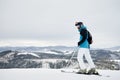 Male skier standing on snowy hill in mountains.
