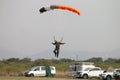 Male skydiver coming in for landing on grass with open brightly