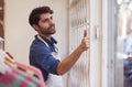 Male Small Business Owner Pushing Back Security Grill And Opening Shop