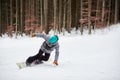 Male snowboarder in blue helmet, risky sliding on flat snow-covered road. Tree trunks and dark forest on background. Royalty Free Stock Photo