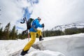 Male snowboarder in bright ski suit climbing on snow-covered foothill using ski-tour equipment. Ski Touring in mountains