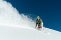 Male snowboarder curved and brakes spraying loose deep snow on f