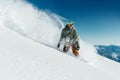 Male snowboarder curved and brakes spraying loose deep snow on