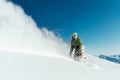 Male snowboarder curved and brakes spraying loose deep snow on