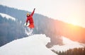 Male snowboarder jumping on the top of the snowy hill with snowboard