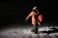 Male snowboarder in orange sport jacket walking on snow with a b
