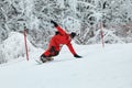 Male snowboarder in a red suit rides on the snowy hill with snowboard, Skiing and snowboarding concept