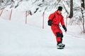 Male snowboarder in a red suit rides on the snowy hill with snowboard, Skiing and snowboarding concept