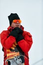 Male snowboarder in a red suit walking on the snowy hill with snowboard, Skiing and snowboarding concept