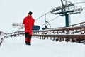 Male snowboarder in a red suit walking on the snowy hill with snowboard, Skiing and snowboarding concept