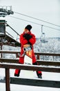 Male snowboarder in a red suit walking on the snowy hill with snowboard, Skiing and snowboarding concept