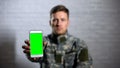 Male soldier in uniform showing smartphone with green screen at camera, app Royalty Free Stock Photo