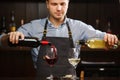 Male sommelier pouring red and white wine into long-stemmed wineglasses