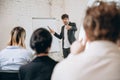 Male speaker giving presentation in hall at workshop. Audience or conference hall. Rear view of unrecognized Royalty Free Stock Photo