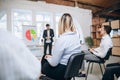 Male speaker giving presentation in hall at workshop. Audience or conference hall. Rear view of unrecognized Royalty Free Stock Photo