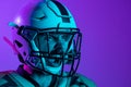 Cropped cside view image of professional american footblall player in protective helmet isolated over dark purple