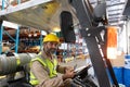 Male staff looking at camera while sitting on forklift in warehouse Royalty Free Stock Photo