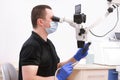 male stomatologist in protective gloves and mask on workplace, looking in dental microscope, Handsome, dentist wearing