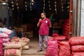 Male storekeeper standing in front of his store, holding a basket of freshly picked red onions Royalty Free Stock Photo
