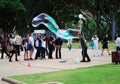 Male street artist makes big soap bubbles with two sticks and thread for group of females in Hyde Park Royalty Free Stock Photo