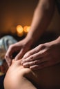 Male strong hands massage back to middle aged woman in dark spa room by candlelight Royalty Free Stock Photo