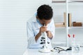 Male student of African descent schoolgirl in science classroom doing chemistry experiment. male student using microscope Look at Royalty Free Stock Photo