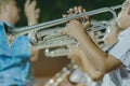 Male student with friends blow the trumpet with the band for performance on stage