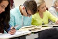 Male student in glasses reading book at lecture