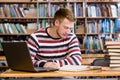 Male student with laptop studying in the university library