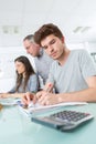 Male student making notes calculator in foreground Royalty Free Stock Photo