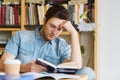 Male student reading book in library Royalty Free Stock Photo