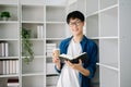 Male student taking notes from a book at library, Young asian sitting at desk doing assignments in college library Royalty Free Stock Photo