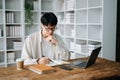 Male student taking notes from a book at library, Young asian sitting at desk doing assignments in college library Royalty Free Stock Photo